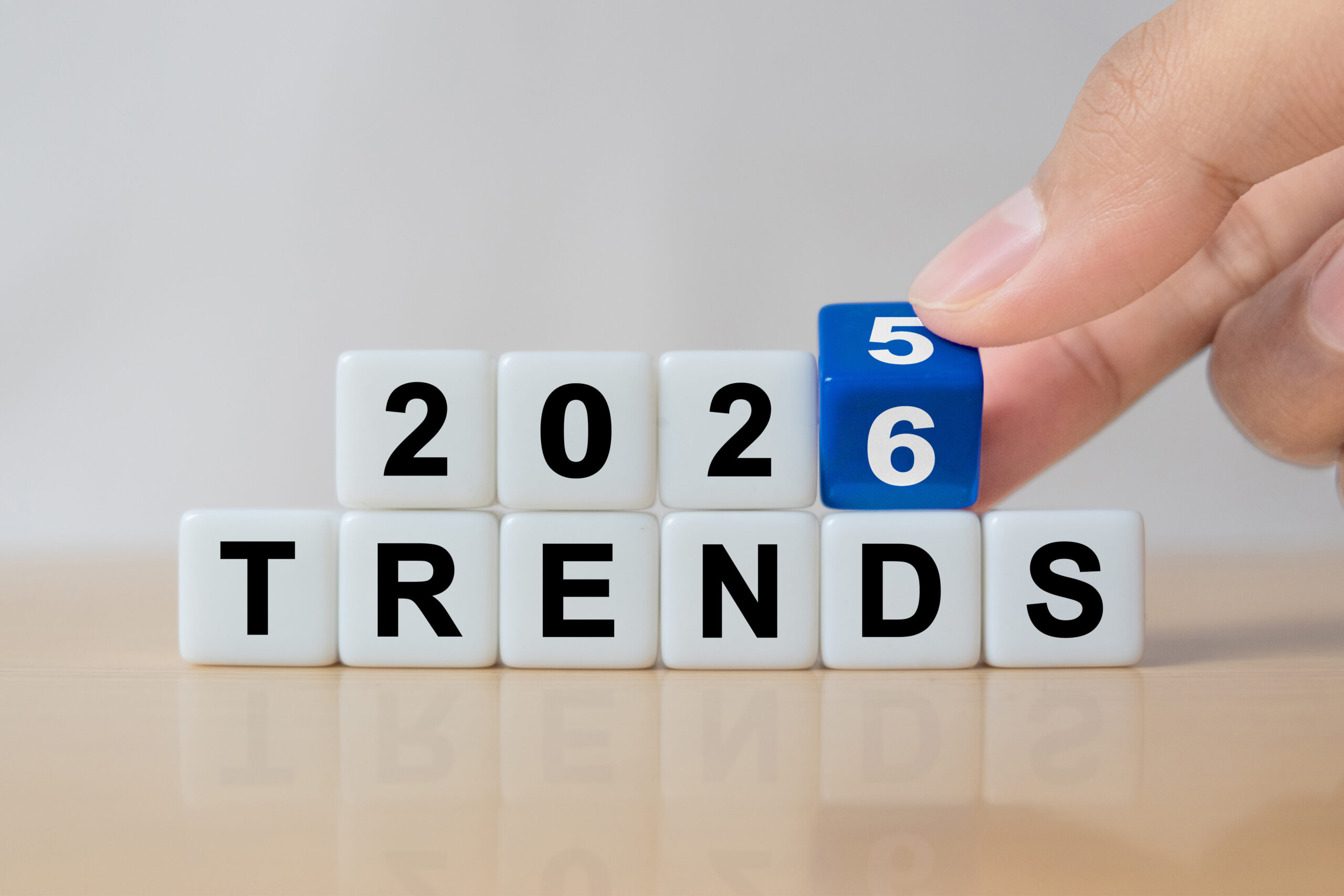 A hand changes the final cube from 2025 to 2026 above the word “TRENDS,” symbolizing the transition into new business trends for the year 2026.